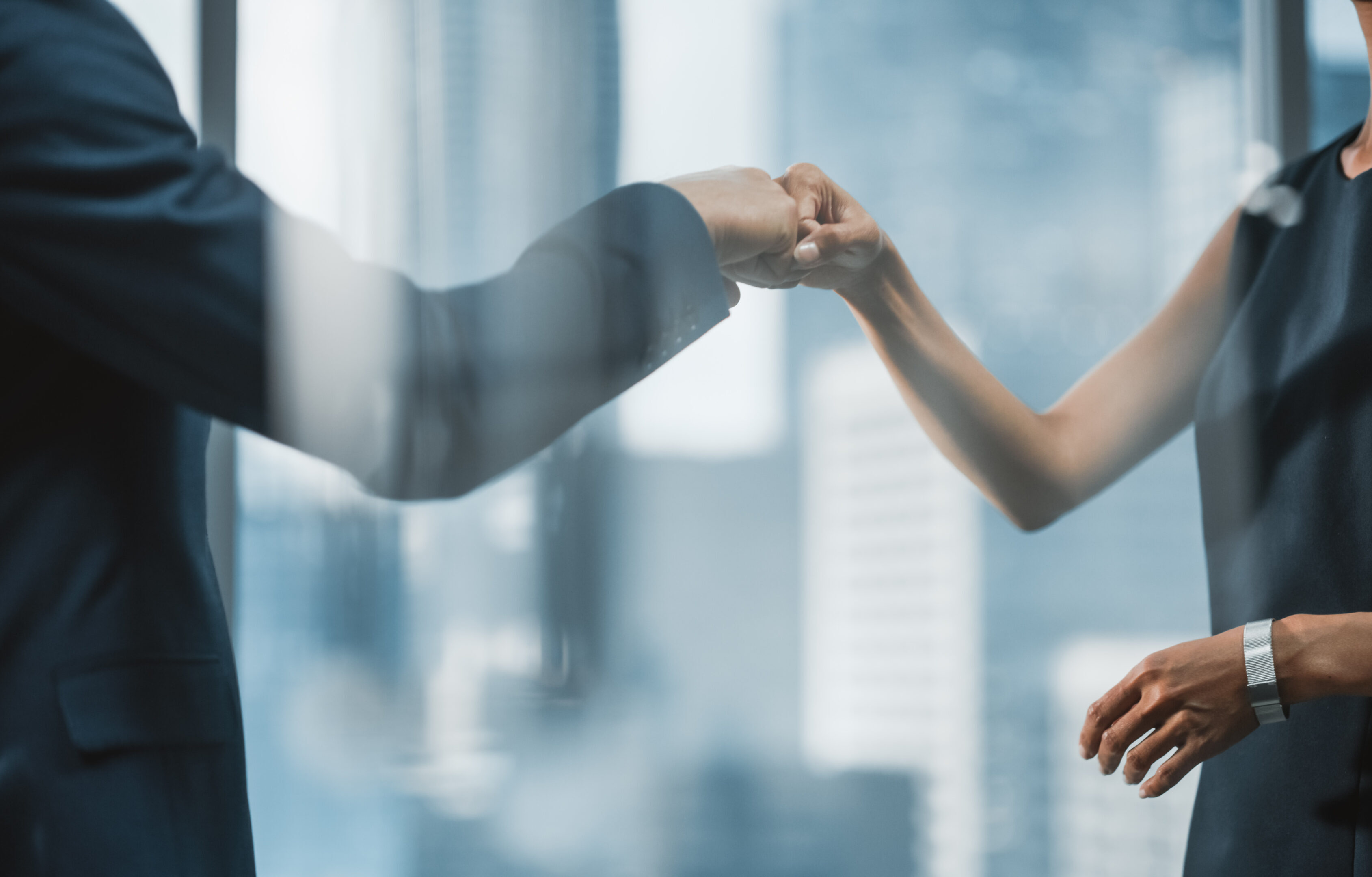 Female and Male Business Partners Meet in Office, Greeting with Fist Bump. Corporate CEO and Finance Manager in City Office. Businesspeople Discuss Real Estate Purchase and Marketing Projects.